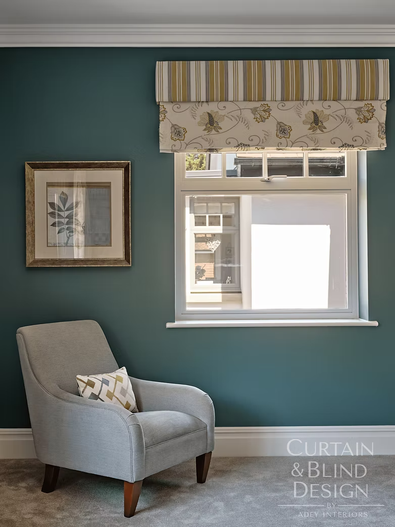 Striped and floral Roman blind above a bedroom window in a teal guest room