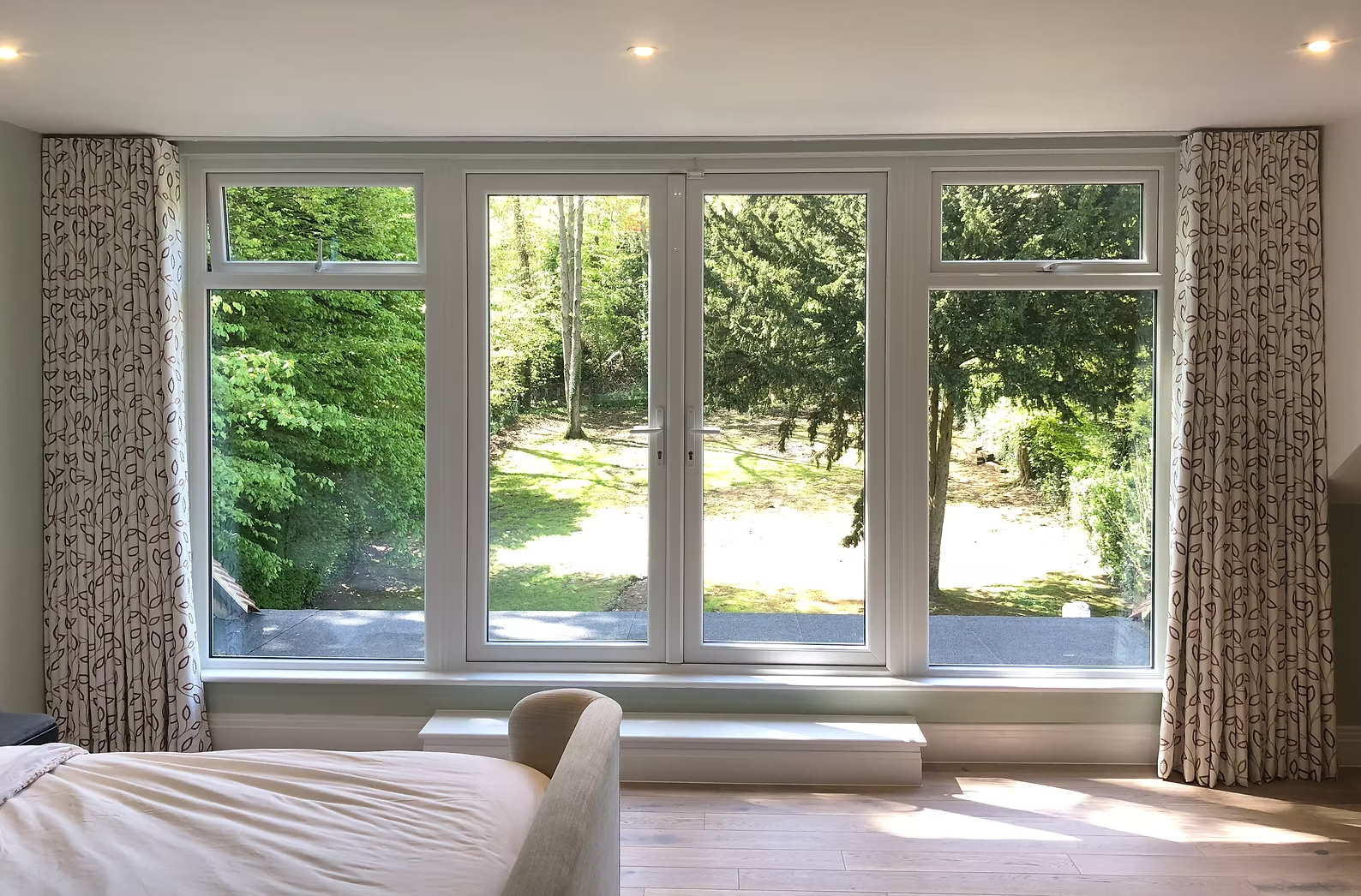 Patterned full-length bespoke curtains framing a multi-pane bedroom window