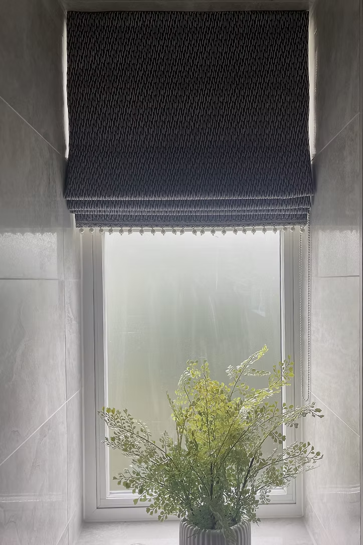 Textured Roman blind with decorative trim fitted above a frosted bathroom window