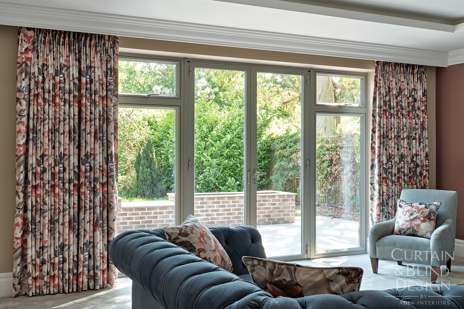 Floral interlined curtains framing glazed doors in a cinema and lounge room