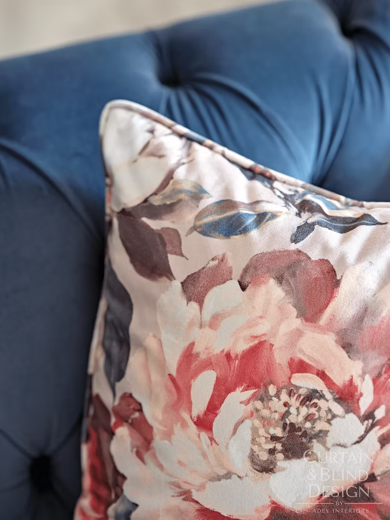 Handmade floral cushion on a deep blue buttoned sofa