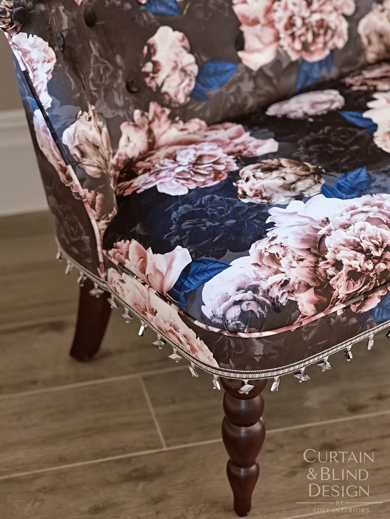 Chair reupholstered in dark floral fabric with decorative trim and beaded fringe