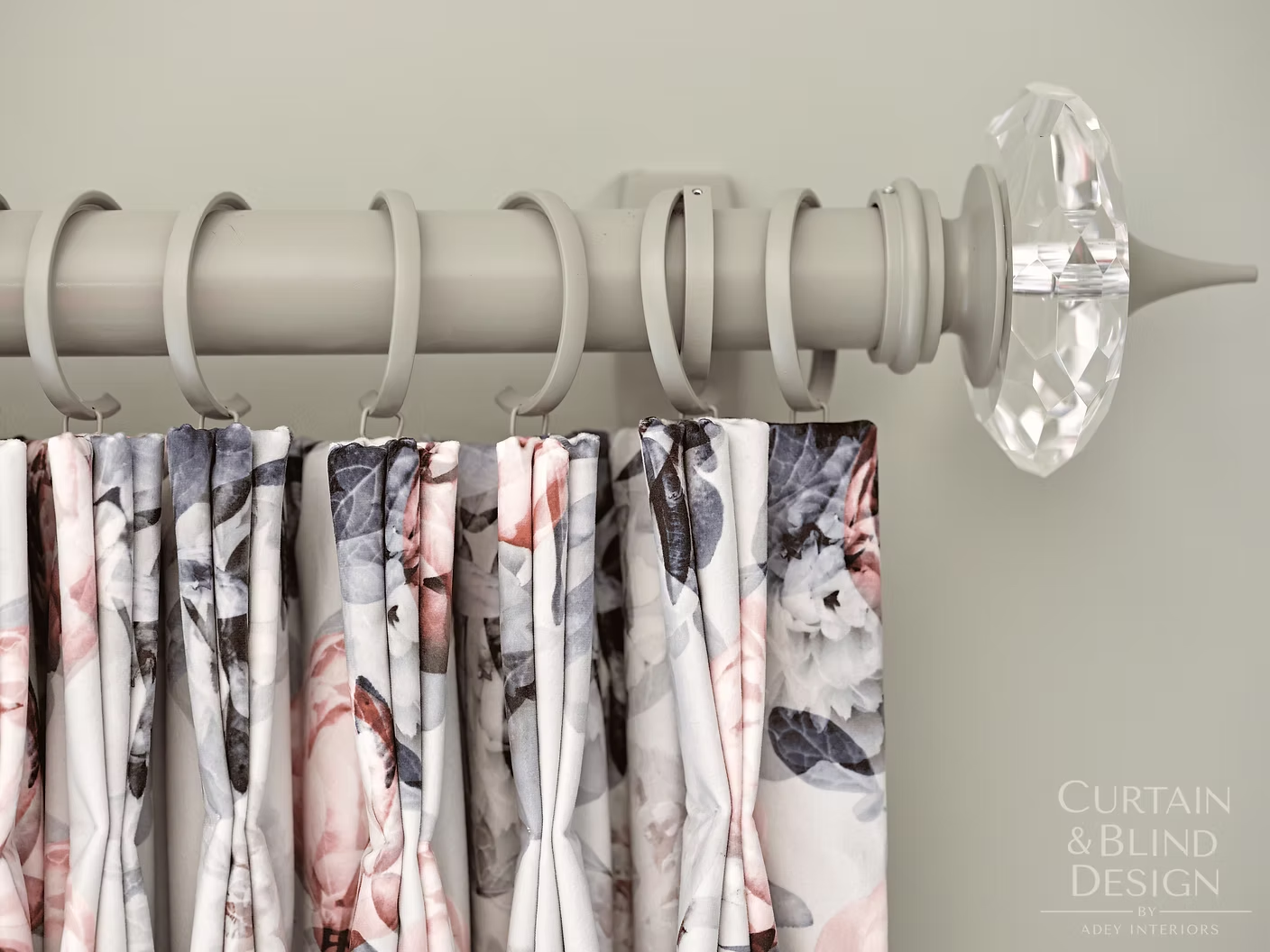Floral curtain hung on a white curtain pole with crystal finial and matching rings