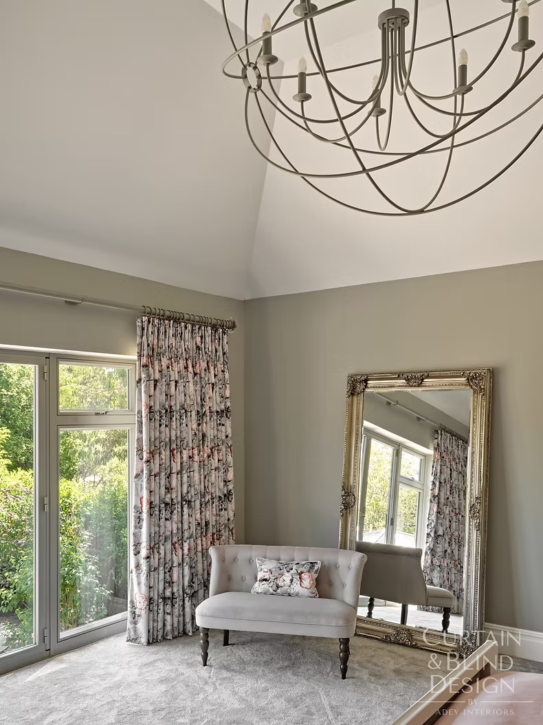Floral bespoke curtains beside glazed doors in a master bedroom seating area