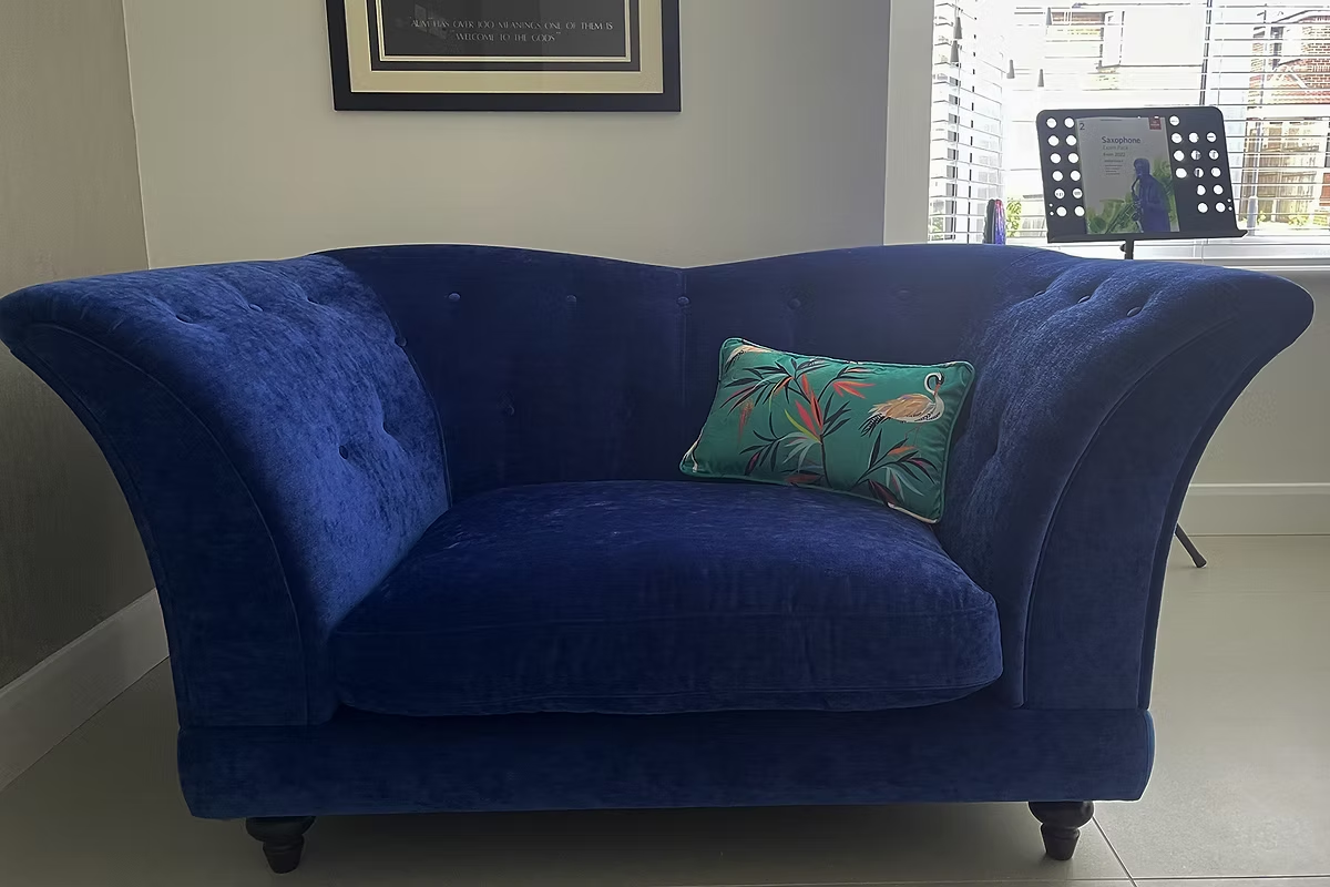 Deep blue reupholstered armchair with a green patterned cushion in a bright room