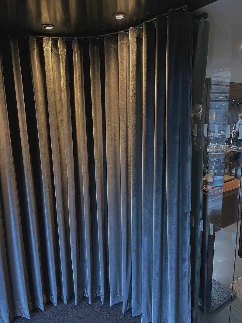 Pleated blue velvet contract curtains dividing a hospitality cloakroom area