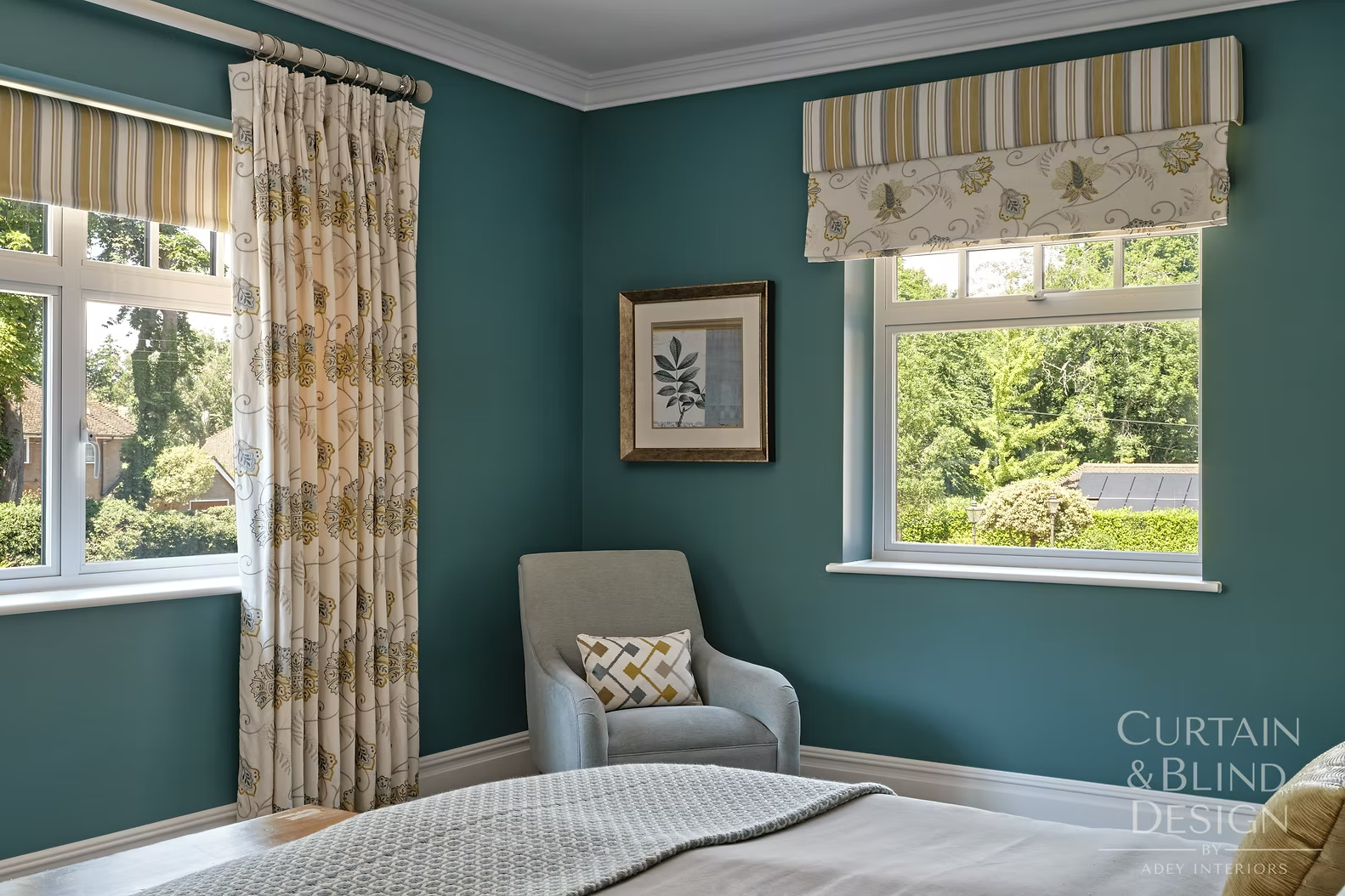 Coordinated window dressing design with floral curtains and a striped pelmet blind in a teal bedroom
