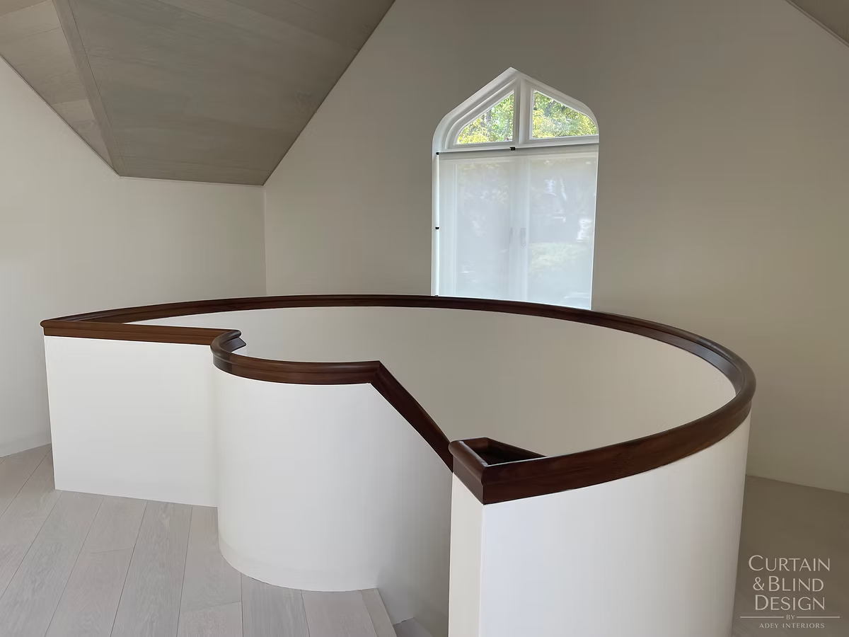 Top-down bottom-up blind fitted to an arched stairwell window above a curved staircase