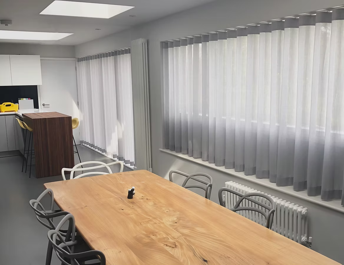 Sheer voile panel curtains hung in long runs across a kitchen and dining room