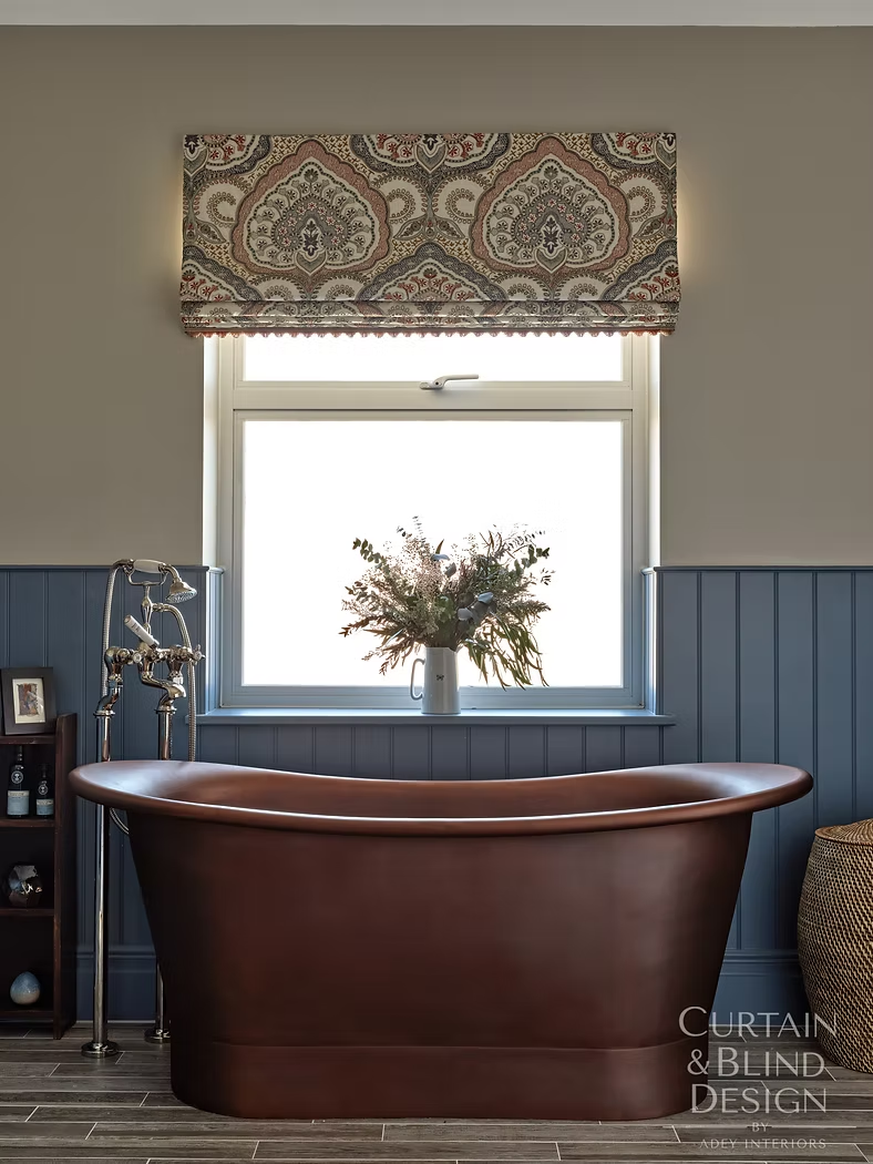 Paisley Roman blind above a freestanding copper bath in a blue panelled bathroom