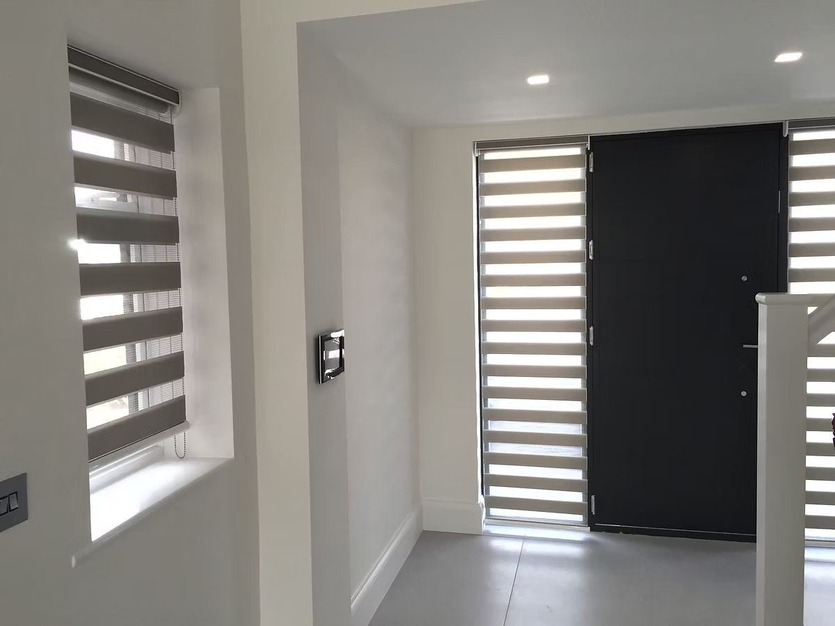 Dark day-and-night blinds fitted beside a black front door in an entrance hall